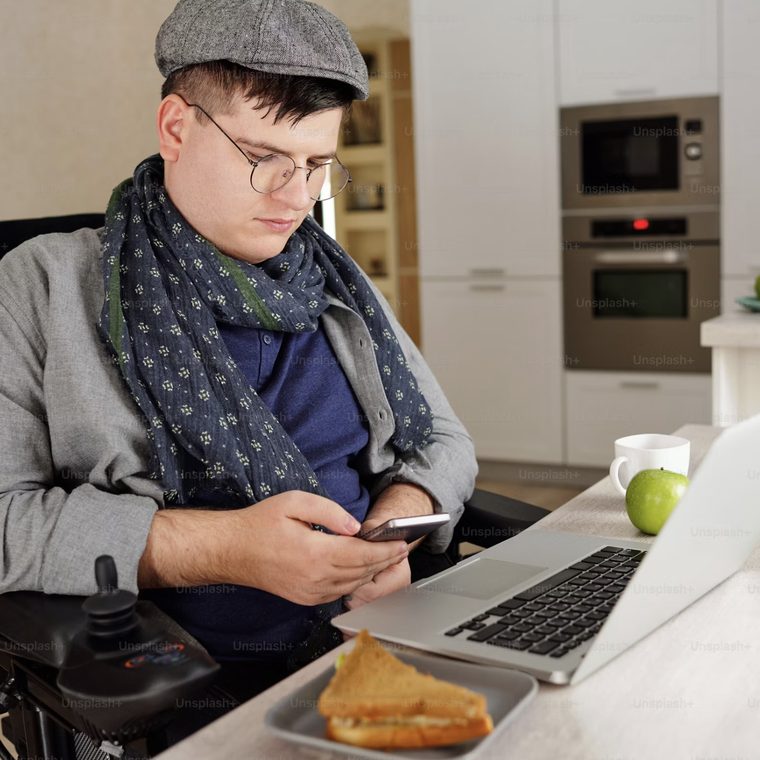 A wheelchair user working at a computer desk at home
